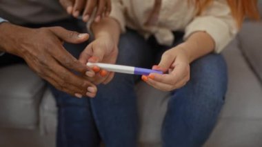 Oturma odasında birlikte oturan bir çift, kadın ve erkek hamilelik testi yapıyorlar, evde sevgi ve ilişki gösteriyorlar.