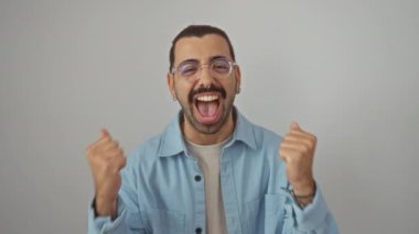 Kot gömlek giyen genç İspanyol adam heyecanlı ve gururlu, başarıyı ve zaferi kollarını kaldırarak kutluyor, izole beyaz arka planda çığlık atıyor.