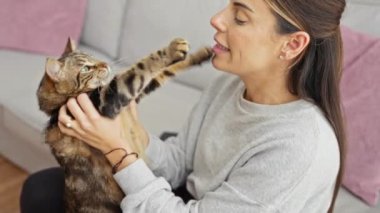 Evcil kedisiyle evcil bir oturma odasında oynayan bir kadın..