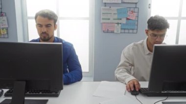 Bilgisayarlar ve dağınık kağıtlarla çevrili masalarında otururken bir ofiste yumruklarını tokuşturarak çalışan iki İspanyol yoldaşlık ve takım çalışmasını gösteriyor.