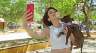 Genç bir kadın köpeğiyle birlikte gün boyunca şehir parkında selfie çekiyor..