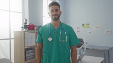 Yeşil önlüklü ve steteskoplu genç yakışıklı veteriner kliniğinde kollarını kavuşturmuş duruyor..