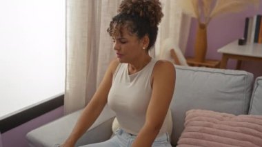 Genç bir kadın, rahat bir oturma odasında kanepede uzanıyor, samimi ve rahat bir an sergiliyor.