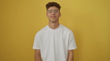 Zafer, beyaz tişört giyen genç İspanyol adam gururlu ve heyecanlı, kollarını kaldırmış, sarı arka planda çığlıklar atıyor.