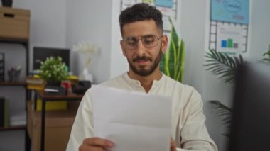 Ofisteki genç İspanyol adam, bir belgeyi heyecan ve neşeyle okurken olumlu bir başarıyı kutluyor..