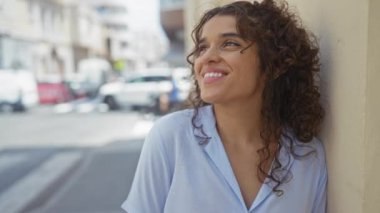 Genç, güzel bir kadın, esmer saçlı, gülümseyen bir kadın. Gündüz vakti bir şehir sokağında dururken..