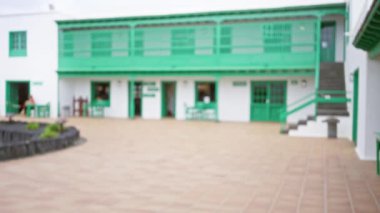 Bulanık koloni tarzı bina. Arka planda yeşil aksanlı kadın var.