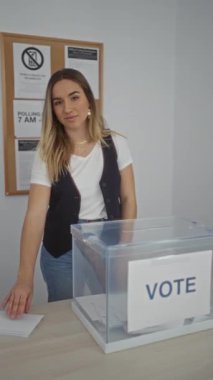 Çekici, sarışın bir kadın, kapalı bir üniversite odasında oy veriyor..