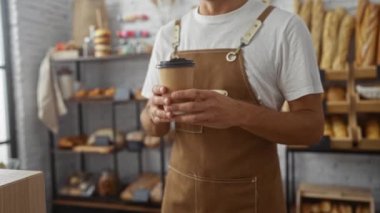 Barista sıcak bir fırında kahve servisi yapıyor ve arka planda taze pişmiş ekmek rafları var.
