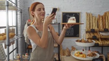 Pastanede arka planda çeşitli hamur işleri ve ekmeklerle fotoğraf çeken bir kadın.