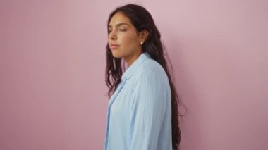 Esmer saçlı, kapalı gözlü, izole edilmiş pembe arka planda açık mavi gömlekli bir kadın.