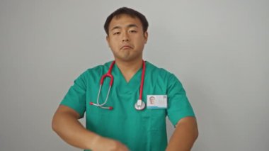 Üniformalı doktor, kollarını çapraz yapmış genç Çinli adam, beyaz arka planda soyutlanmış, mutlu, gülümseyen, pozitif görünen.