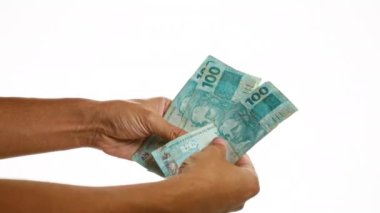Eller Brezilya 'nın 100 banknotunu soyutlanmış beyaz arka planına karşı tutuyor