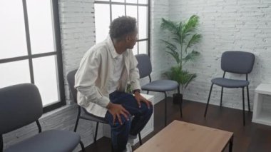 Genç Afrikalı Amerikalı bir adam kapalı bir odada bekliyor. Kol saatinin saatini kontrol ediyor. Büyük camlardan süzülen modern dekorlu ve ışıklı bir sandalyeye oturuyor..