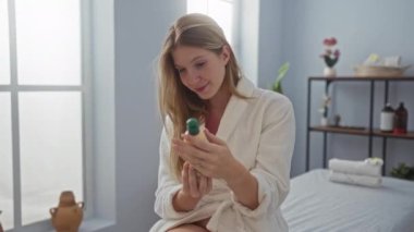 Cübbeli kadın, yumuşak ışık ve modern sağIık dekoruyla ürünü sakin spa ortamında tutuyor.