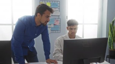 Bir ofis çalışma alanında birlikte çalışan İspanyol adamlar, biri mavi gömlekli, gülümseyen ve bir meslektaşını yumruklayan, takım çalışması ve işbirliği gösteren bir bilgisayar..
