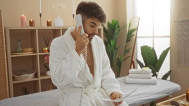 Kaplıcada sakallı, bornoz giyen, telefonla konuşan ve sakin bir sağlık merkezinde evrakları tutan genç bir adam..