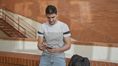 Genç, yakışıklı, İspanyol bir adam şehrin arka planındaki akıllı telefonuna odaklanmış..