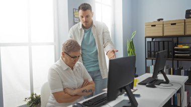 Ofiste çalışan kadın ve erkek, modern bir iş ortamında bilgisayarlarla iş konuşuyorlar.