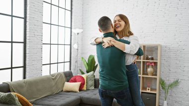 A cheerful woman embracing a man in a cozy living room, expressing affection and joy. clipart