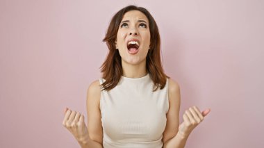 Latin kökenli genç bir kadın pembe bir arka plana tutkuyla bağırıyor, duygularını ve güzelliğini gösteriyor..