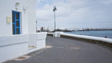 Lanzarote 'de beyaz evler, mavi kapılı İspanya ve bulanık bir arka planı olan bir sahil caddesi.