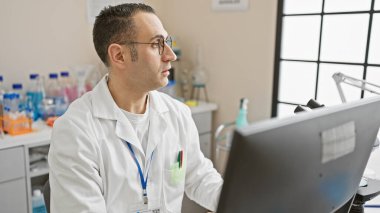 Hispanic male scientist working in a laboratory setting, researching while using a computer. clipart