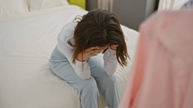Sıkıntılı bir İspanyol kadın, kapalı bir yatakta oturuyor. Üzüntü ve tefekkür duygularını gösteriyor..