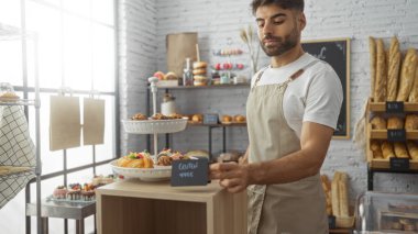 Ekmek ve hamur işleriyle bir fırında çalışan genç adam..