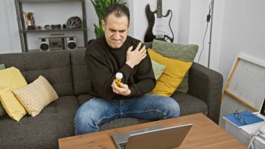 İçerideki İspanyol adam sıcak bir oturma odasında ilaç tutarken omuz ağrısı çekiyor.