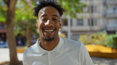 Güneşli bir günde şehir parkında gülümseyen sakallı yakışıklı Afrikalı Amerikalı adam..