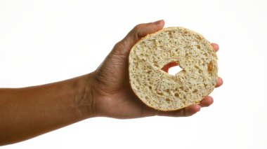 İzole edilmiş beyaz arka planda düz bir simit tutarken