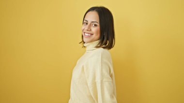 Neşeli bir portre için sarı izole edilmiş arka planda poz veren, zarif saç stili olan gülümseyen genç İspanyol kadın..