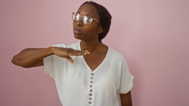 Çekici genç Afrikalı Amerikalı kadın elini pembe bir arka planda tutarak boğazını keserek acil ya da tehlikeli olduğunu ifade ediyor..