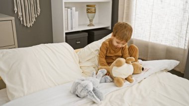 Kafkasyalı genç bir çocuk, içi güzel dekore edilmiş bir yatak odasında doldurulmuş hayvanlarla oyun oynamaktan hoşlanıyor.