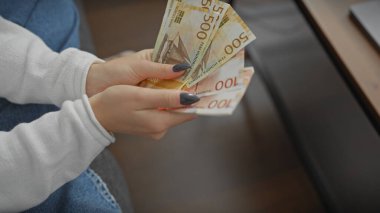 Evde Norveçli bir kron tutan genç bir bayanın yakın plan çekimi. Kapalı mekanda gündelik bir hava yayıyor..