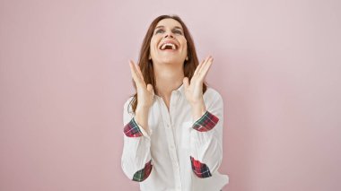 Neşeli orta yaşlı bir kadın pembe izole bir arka plana gülümseyip el çırpıyor..