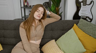 Rahat genç bir kadın şık bir dekorla çevrili rahat bir kanepeye uzanır..