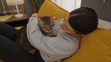 Genç bir İspanyol kadın, sıcak bir yatak odasının içinde kedisiyle sarılıp sıcak, kapalı bir ev dekorasyonu sergiliyor..