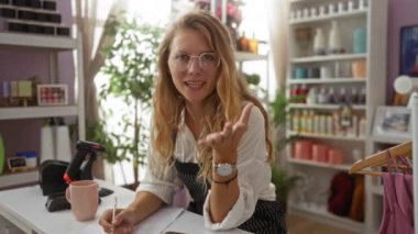 Ev dekorasyonunda çalışan, kalemle yazan, etrafı dekorasyon malzemeleriyle çevrili, sarı saçlı, gözlüklü, güzel dekorlu, parlak bir kadın, iç mekan mağazası.