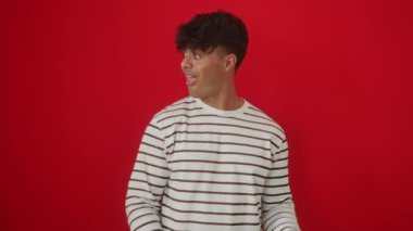 Çizgili tişörtlerle gülümseyen bir adam, genç İspanyol erkek ayakta duruyor ve parmaklarıyla arka tarafı işaret ediyor.