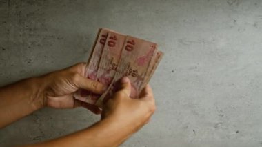 Türk parası gösteren beton bir arkaplan karşısında 10 lira tutan eller