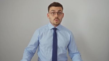 Genç İspanyol bir adam gömlek ve kravat giyiyor ve ağzı açık şaşkınlık ve şaşkınlık içinde, izole beyaz arka plan üzerinde duruyor, korku ve inançsızlık bir yüz göstermektedir