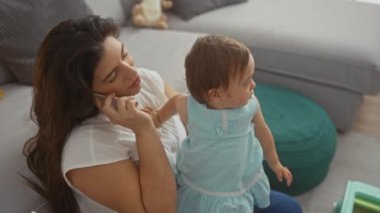 Anne kızını telefonda oyuncaklarla tutarken birden fazla iş yapıyor. Tipik bir aile evi senaryosu sergiliyor. Sevgi ve özen gösteriyor..