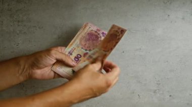 Arjantin pesolarını iki eliyle somut bir zemine karşı sayan adam.