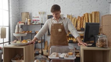 Tezgahın arkasında duran fırında genç bir adam ve çeşitli ekmek ve hamur işleri modern bir iç mekanda sergileniyor.