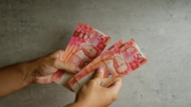 Filipinler 'deki beton bir arka planda 50 peso' luk banknotlar sayan eller, Filipinler 'de sergilenen paralar.