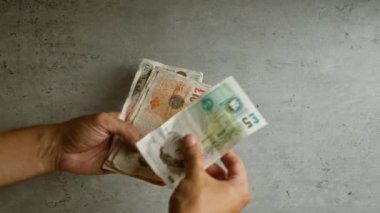 İngiliz sterlinini tutan eller beton bir arka planda, İngiltere 'de para sayıyor..
