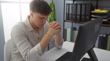 Modern bir ofisteki bilgisayarın başında çalışan genç bir adam, düzenli dosyalarla dolu raflarla çevrili, aynı zamanda derin düşüncelere dalmış..