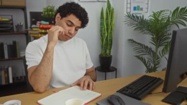 Ofisteki genç İspanyol bir adam, kafasında dinlenme ve masasında açık bir defterle uykuya dalıyor..